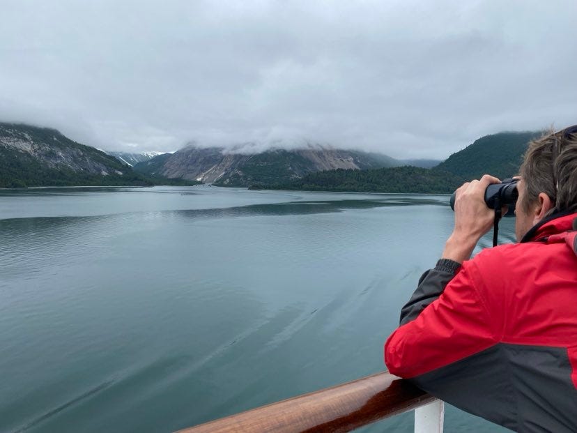 handsome man viewing humpback whales from a distance on the open deck of a Princess Cruise Ship in Alaska handsome man viewing humpback whales from a distance on the open deck of a Princess Cruise Ship in Alaska