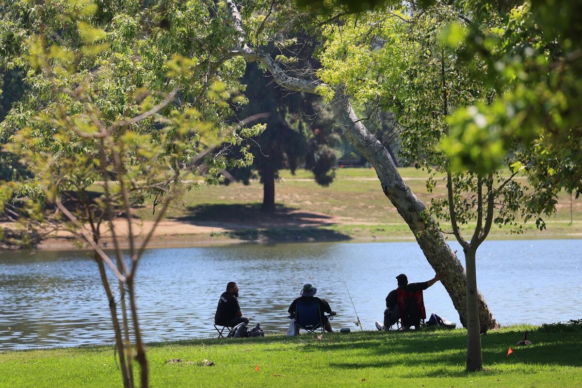 Fishermen relax in the shade on a hot, sunny day as they fish at Legg Lake in Whittier Narrows Recreation Area.