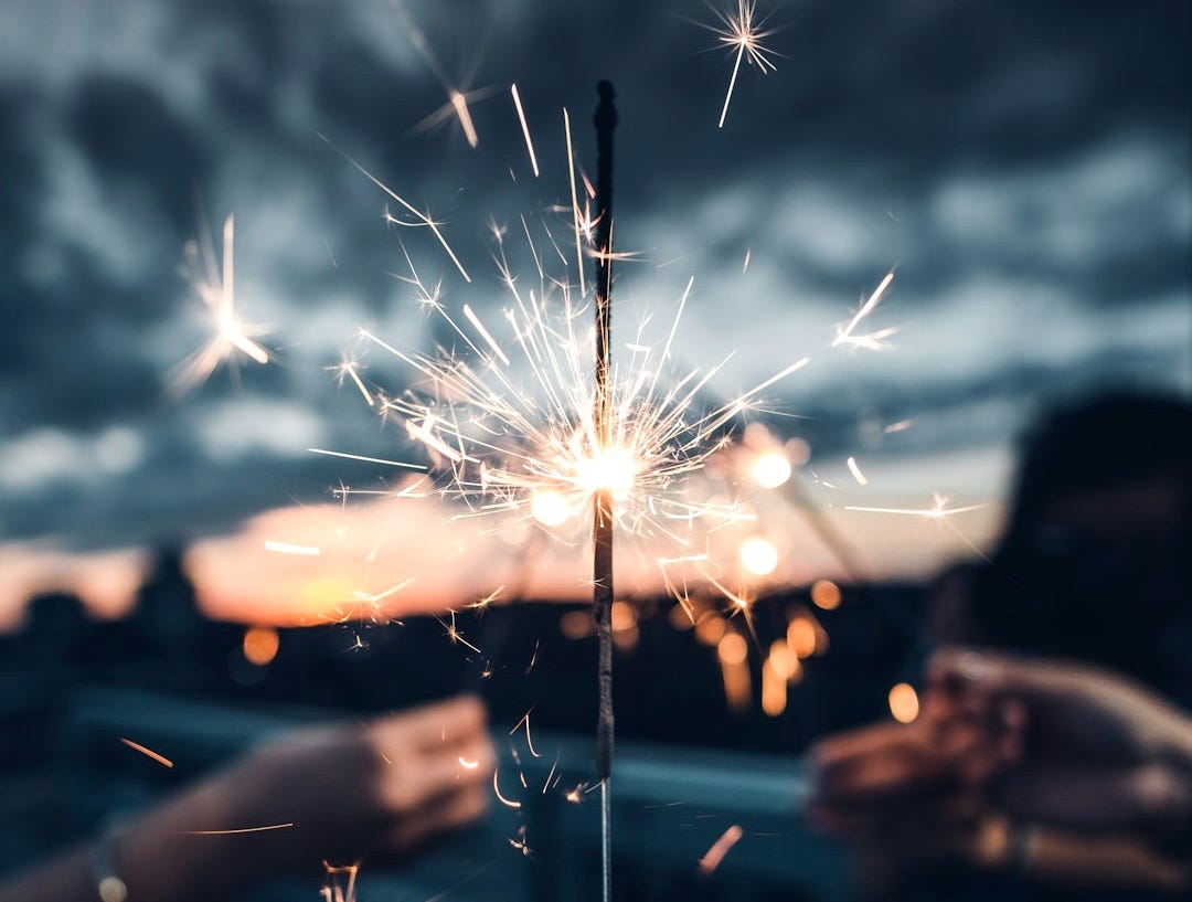 photo of person holding lighted sparkler