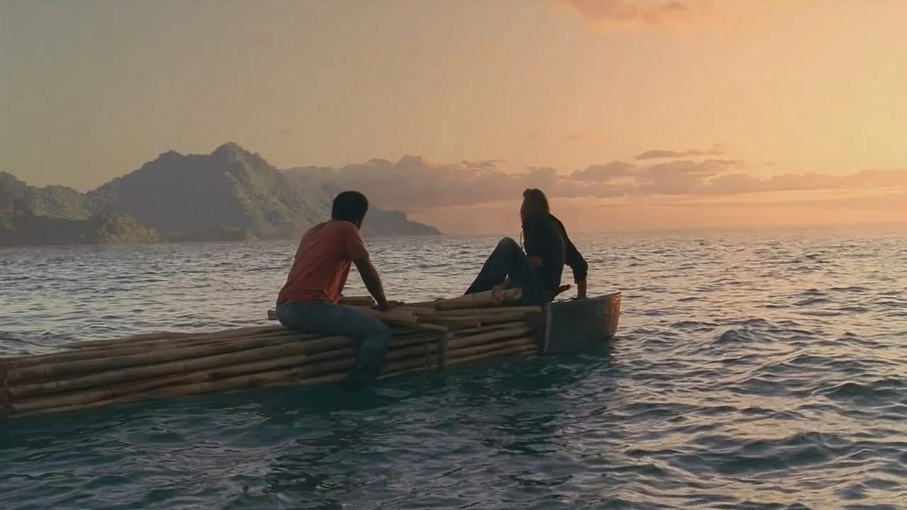 Michael and Sawyer float on a pontoon in the ocean at sunrise. In the distance, they see the mountains of the island.