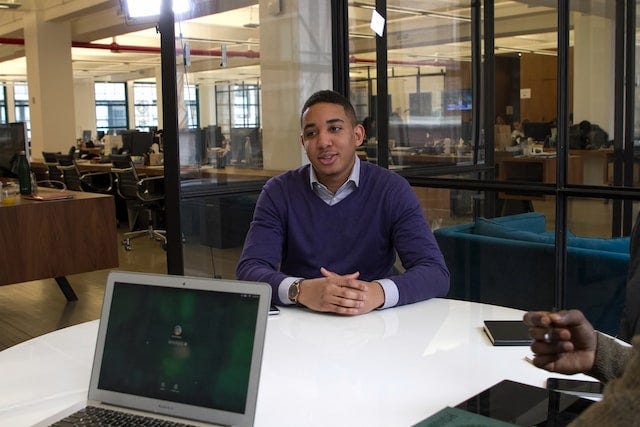 Man in interview in a conference room with glass walls in an office.