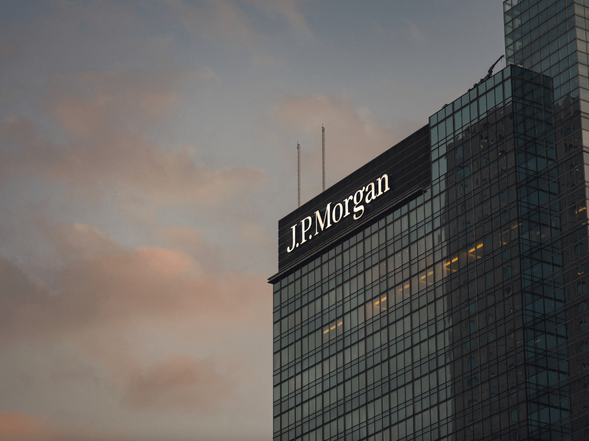 Sede da JPMorgan em Hong Kong. Arranha céu de vidros escuros em dia de céu azul com nuvens avermelhadas.