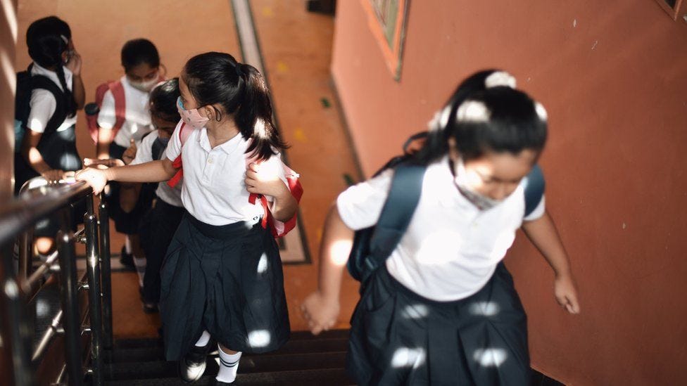 Schoolchildren wearing masks walking up stairs