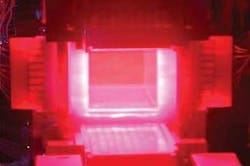 FIGURE 1. The 10-cm-square ceramic Nd:YAG slab at one end of Lawrence Livermore’s solid-state heat-capacity laser glows from the pump light from the high-power pump arrays on four sides of the YAG slab, visible because the camera was not filtered to block the 808 nm pump wavelength. The camera did not record the 1064 nm output.