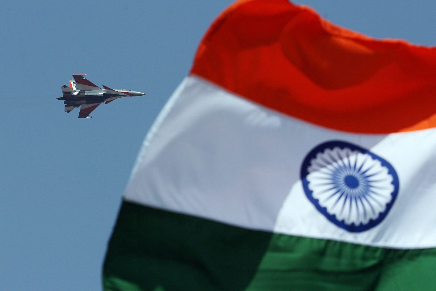 An Indian Air Force flies past an Indian flag in Bangalore, India.