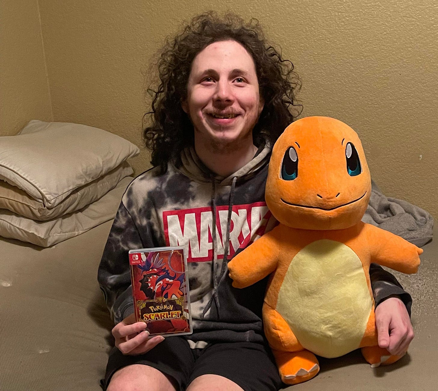 A photograph of Danior with a copy of Pokémon Scarlet and a giant Charmander plush