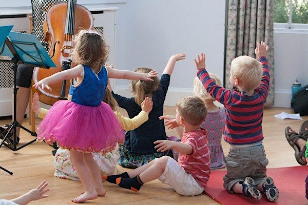 group of small children watching someone play the cello