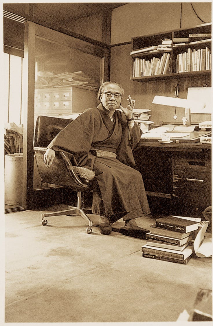 This may contain: an old photo of a man sitting at his desk in front of a book shelf