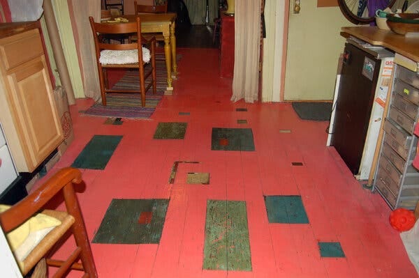 Imperfect red floorboards are shown. 