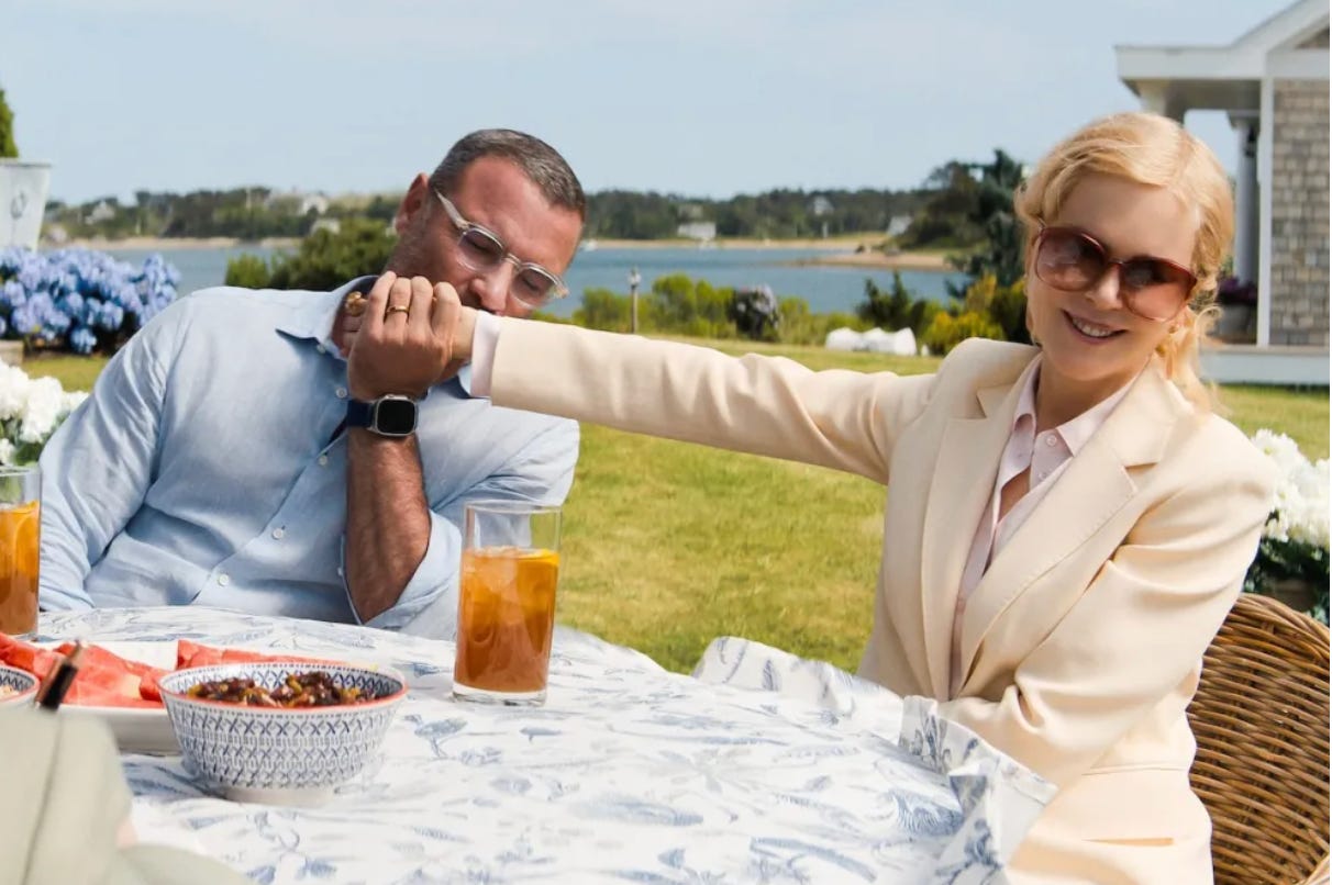 Liev Schrieber kisses Nicole Kidman's outstretched arm at a table in their garden.