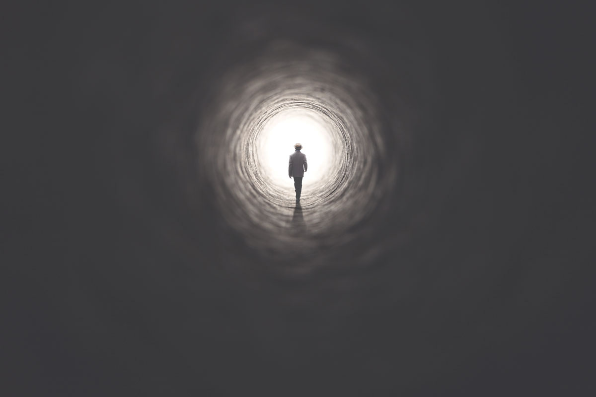 Man in Dark Tunnel Approaching Light