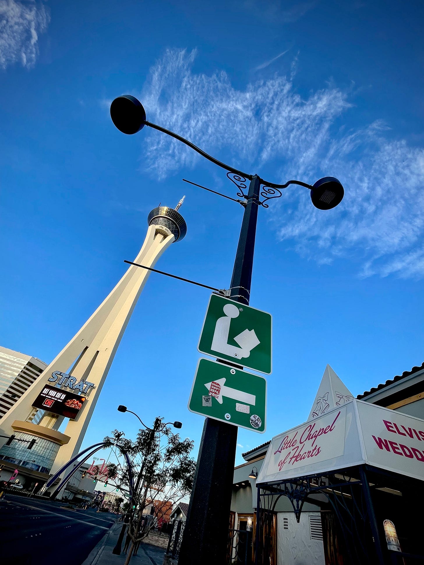 Looking up: The Strat space needle, an old street lamp with a library sign on it, and the awning of a chapel offering Elvis weddings.