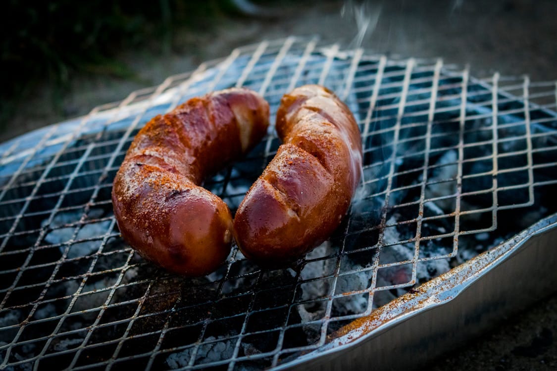 Free Close-up of grilled sausages on a barbecue grill with smoke rising. Stock Photo
