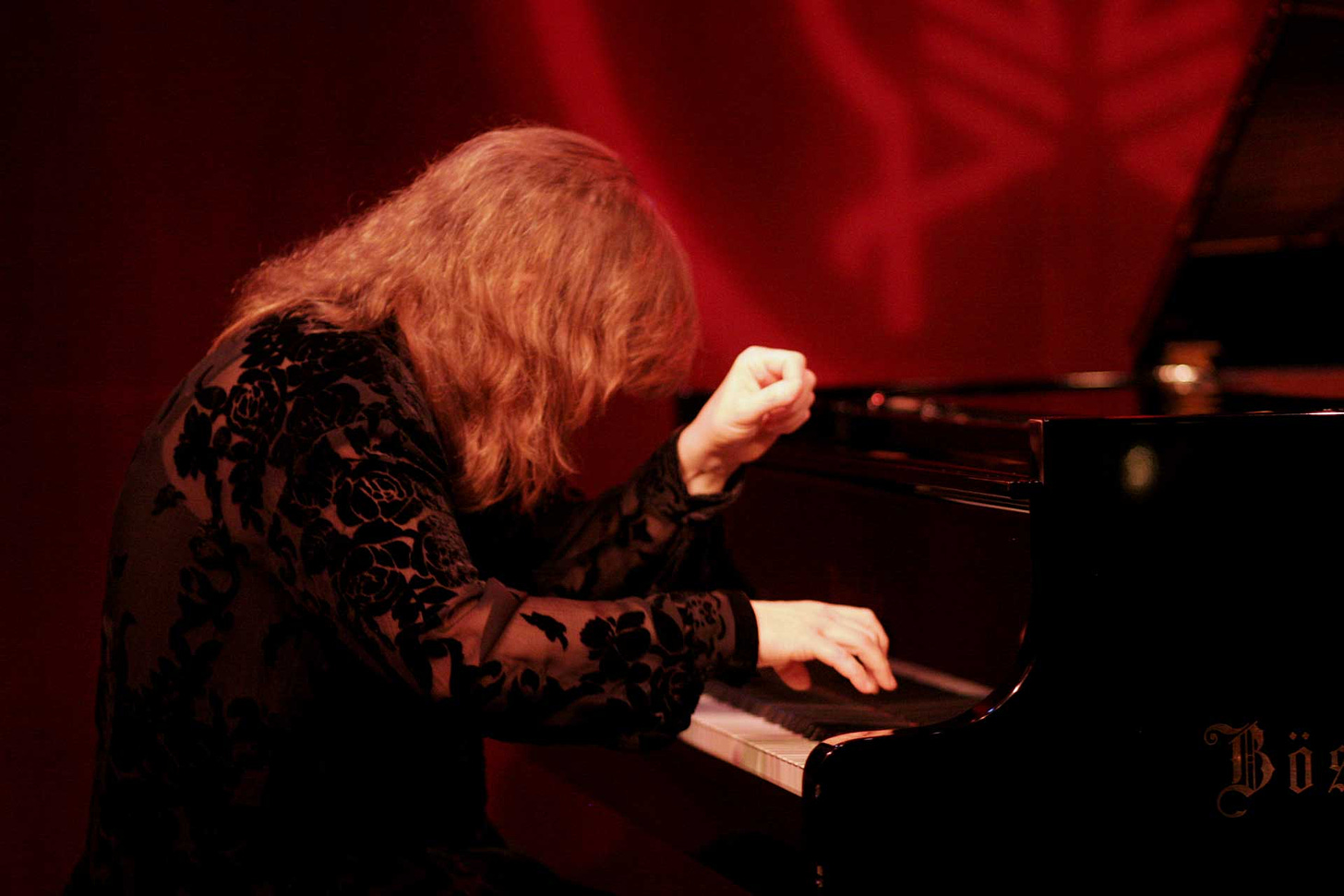 Marilyn Crispell playing a Bösendorfer piano under red lighting