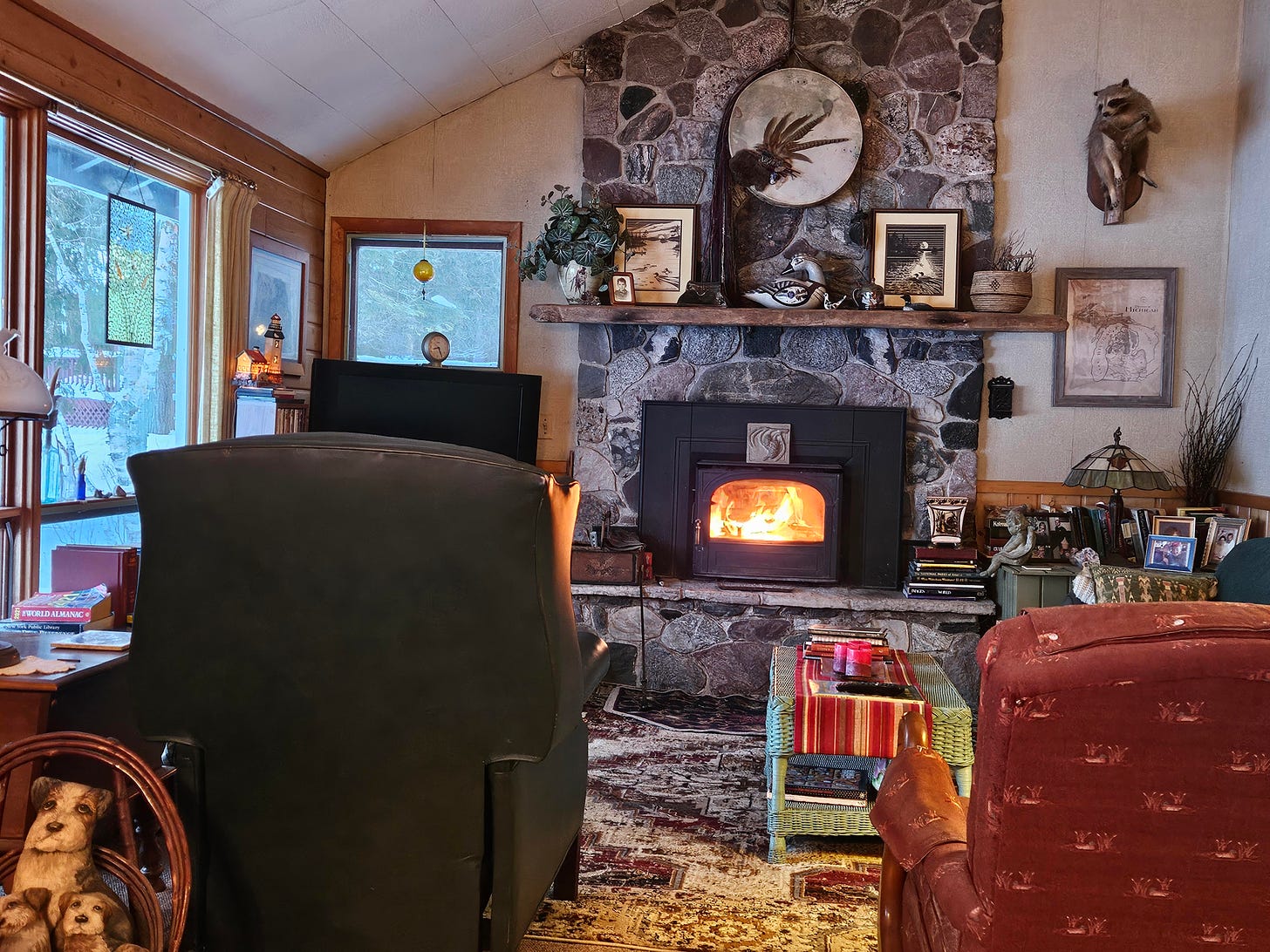 A cabin living room with roaring fire in the stone fireplace.