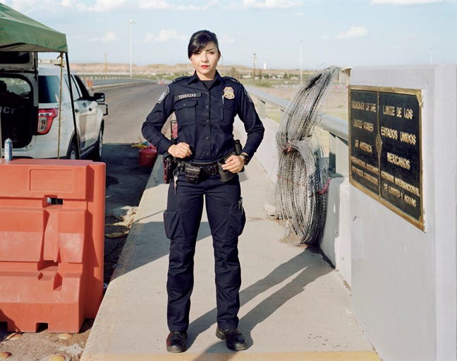 US Customs and Boarder protection officer, female, Hispanic heritage, dark hair in tight bun, dark blue uniform, red lipstick. 