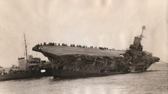 HMS Legion at work during its rescue attempt as Ark Royal’s crew line the edge of the flight deck.