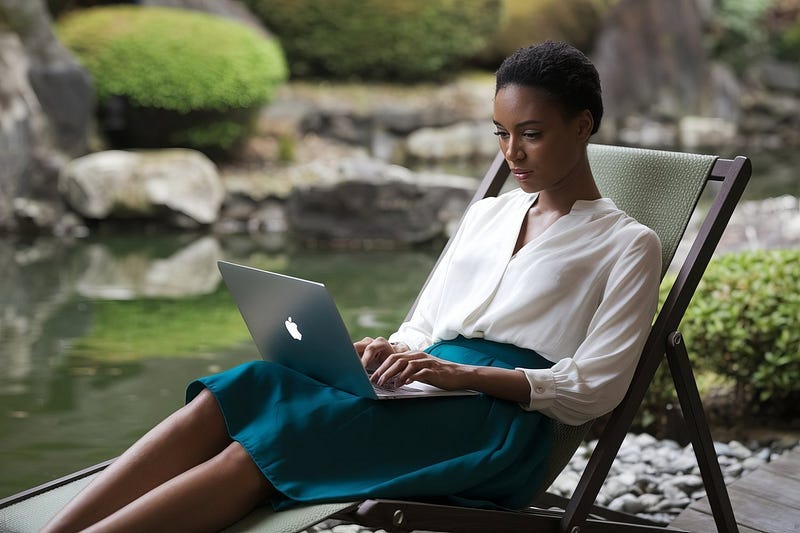 African woman sitting on a deck chair in a Japanese garden typing on her MacBook Pro.