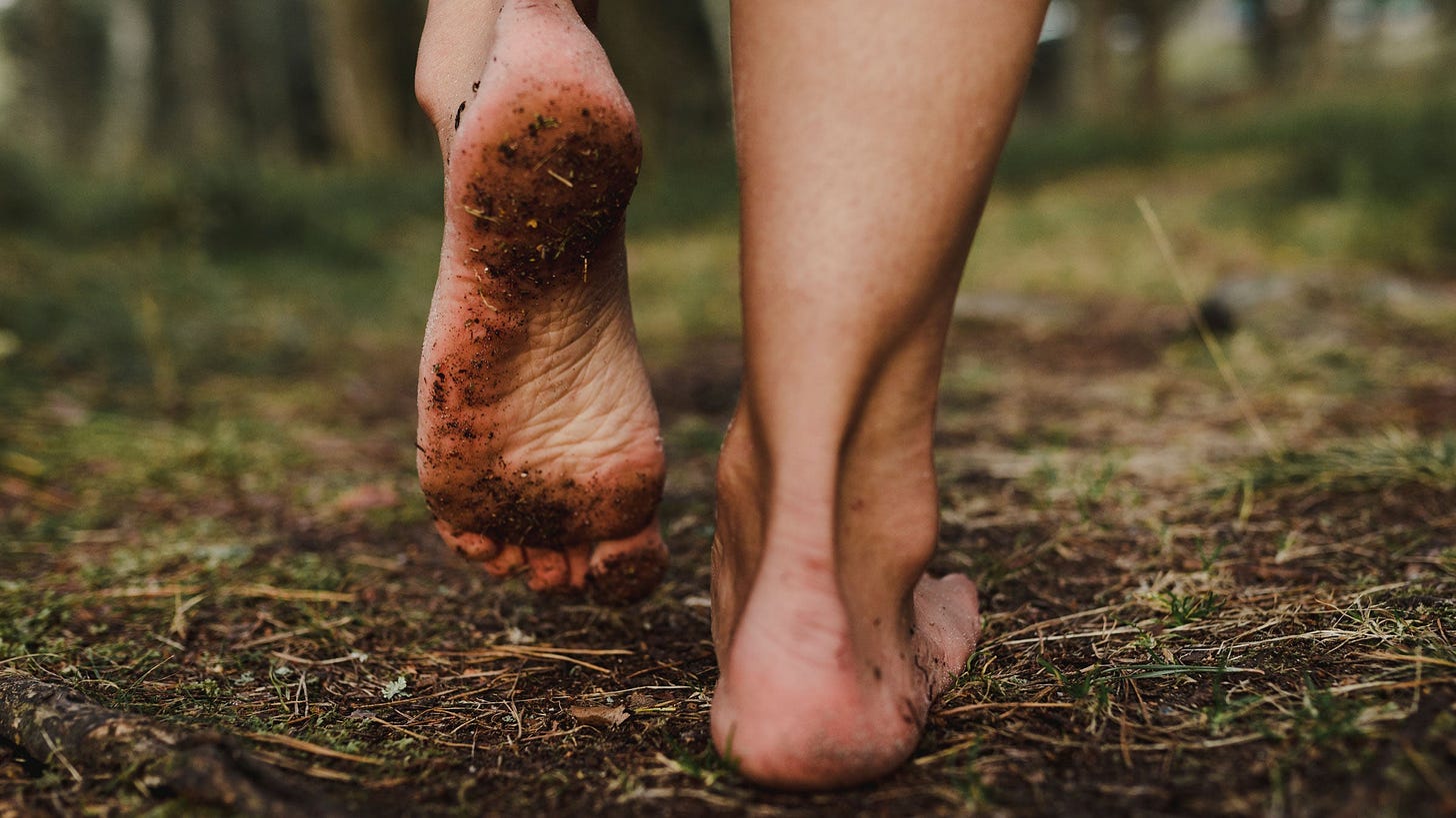 Woman walks barefoot outside, benefits of grounding