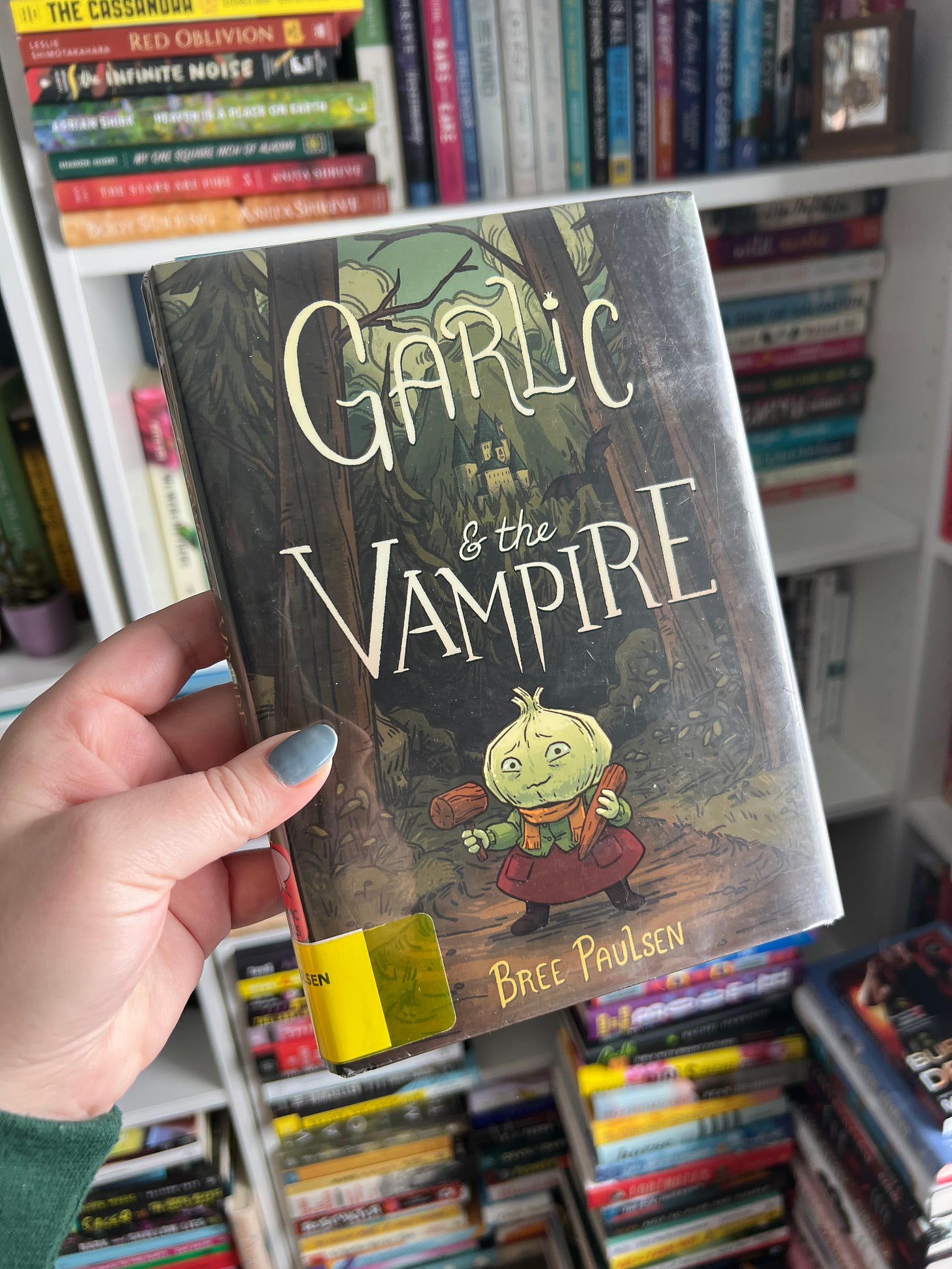 My hand holding a library copy of Garlic and the Vampire