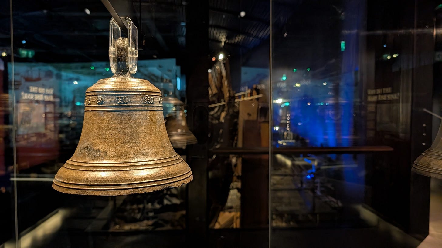 A bell from the ship is in the foreground, with a blurred background of the shipwreck.