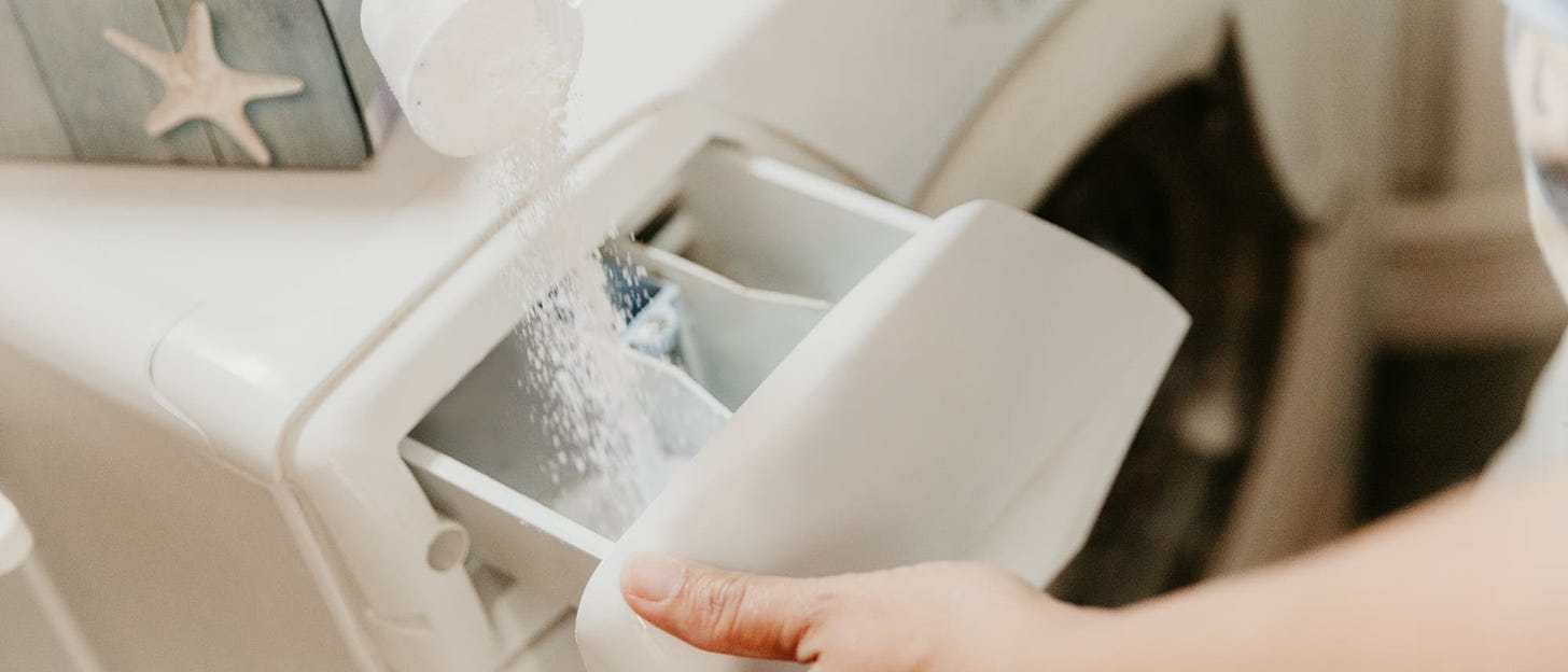 Washing powder is poured into the detergent compartment of a washing machine.