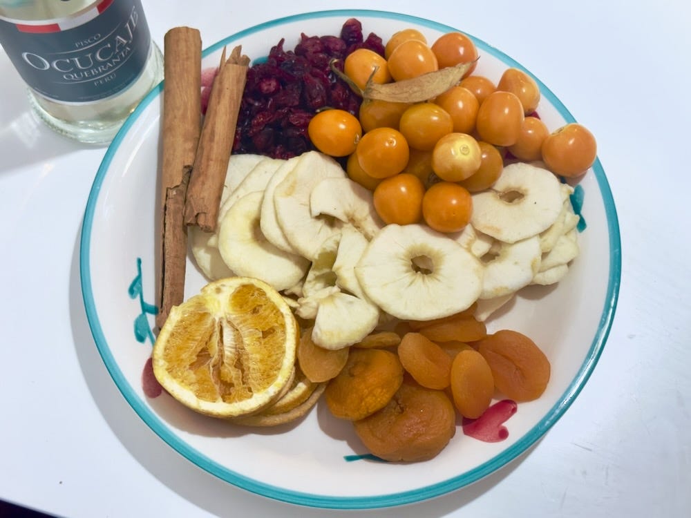 Plate with ingredients for our macerados: cranberries, aguaymanto, apple, apricots, oranges, and cinnamon