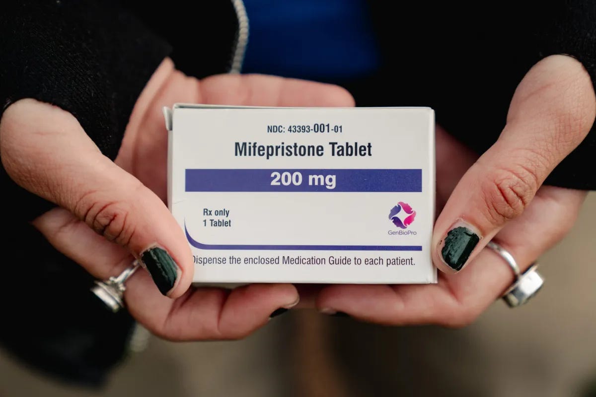 A photo of a white box that indicates it holds 200mg of Mifepristone Tablets being held in someone’s hands.