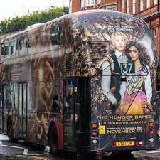 A double decker bus with a Hunger Games TBOSAS poster all over it.