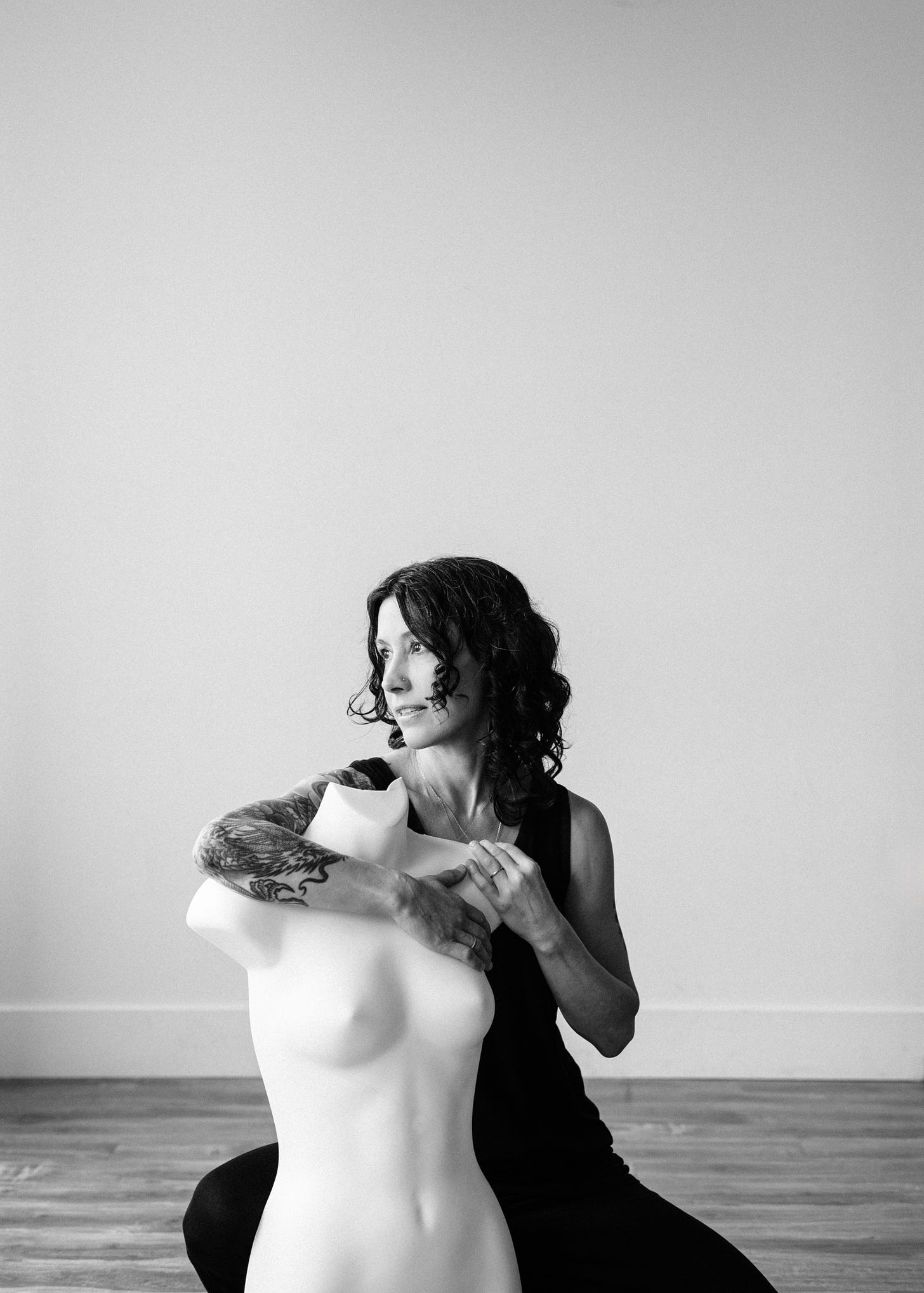 Author dressed in black with arms wrapped around a white mannequin