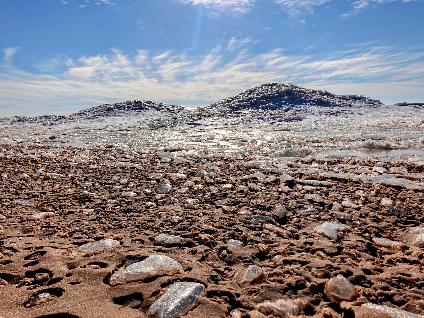 A photo of ice mounds on Lake Michigan, with sparkling ice chunks in the foreground and a bright blue winter sky in the background