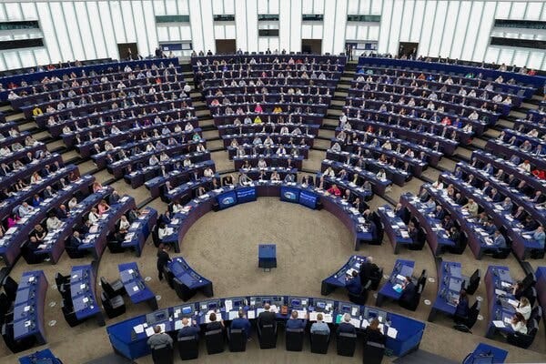 A large meeting room with more than a dozen concentric rows of blue desks.