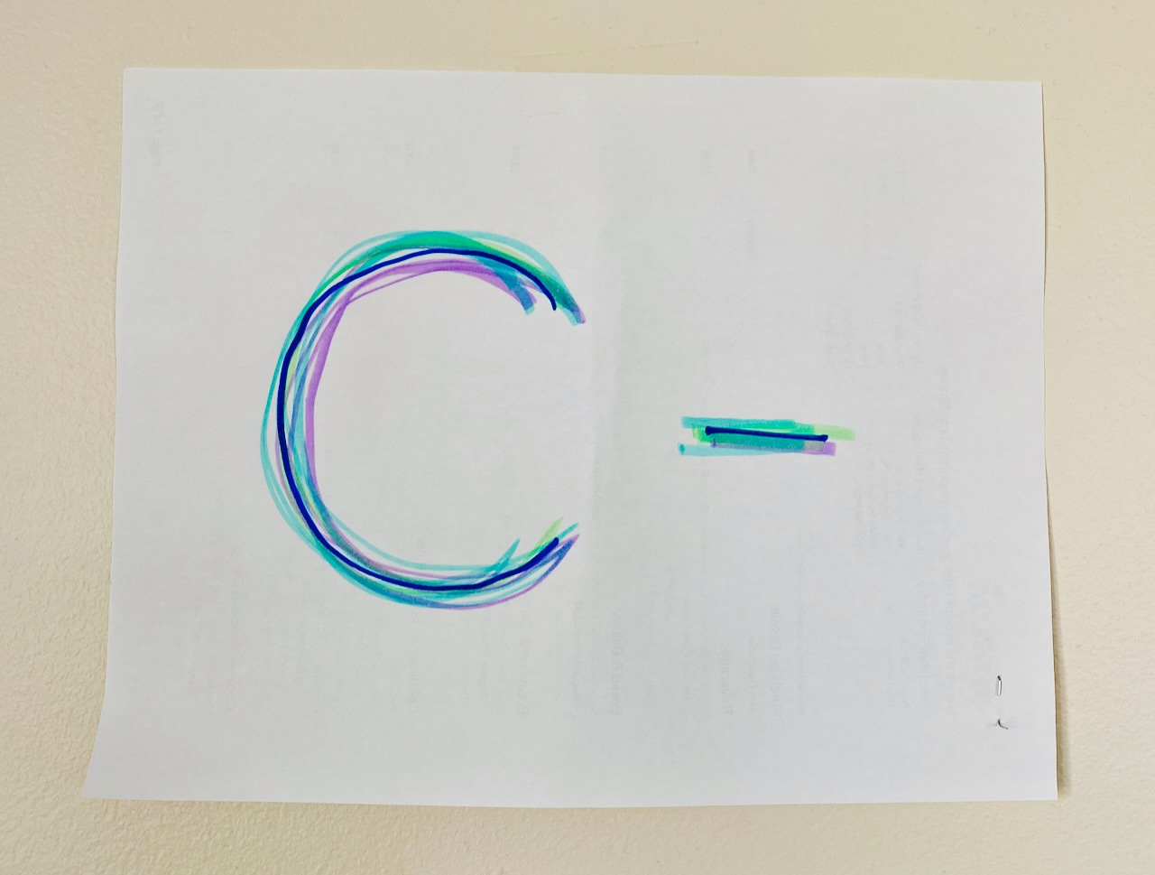 a messy C- written in four colors of marker on a piece of paper, taped to the wall.