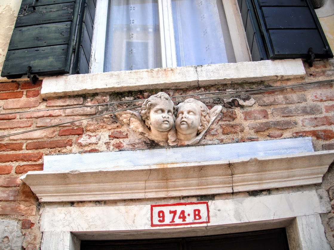 Architectural details in the form of small cherubs below a window in Venice.
