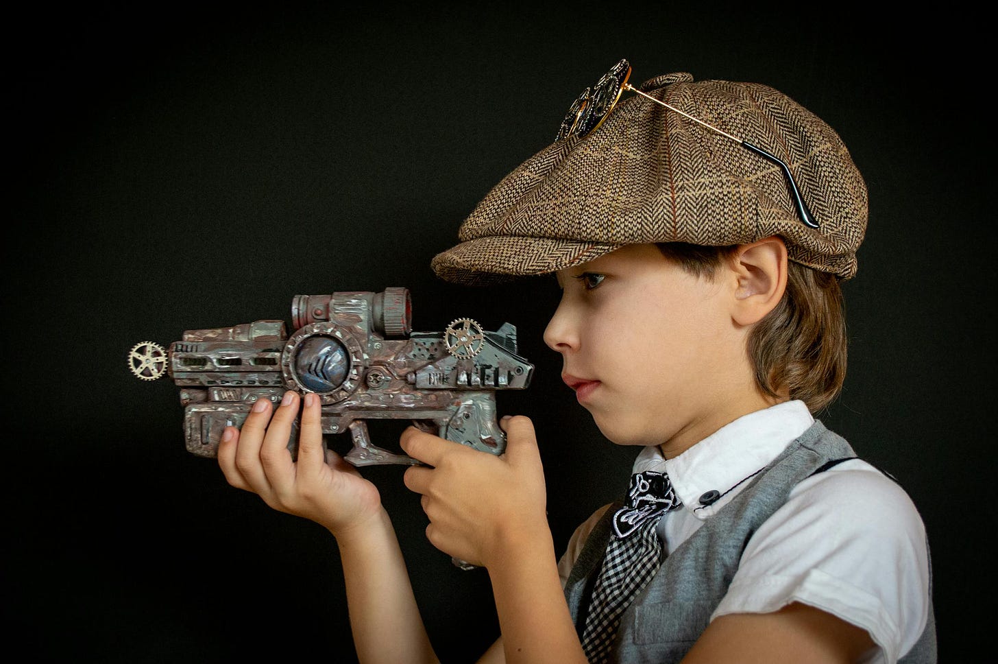 Child in a cap holds an old toy gun