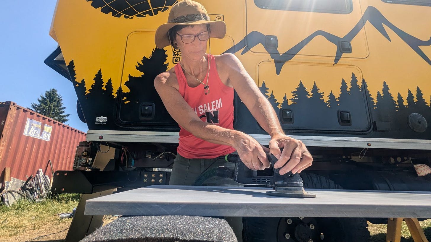 Sherry sanding a slab of countertop material, with the rays of the sun beating down