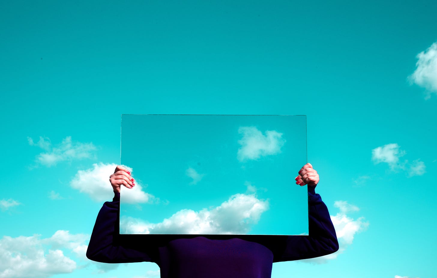 Person holding a mirror reflecting the sky