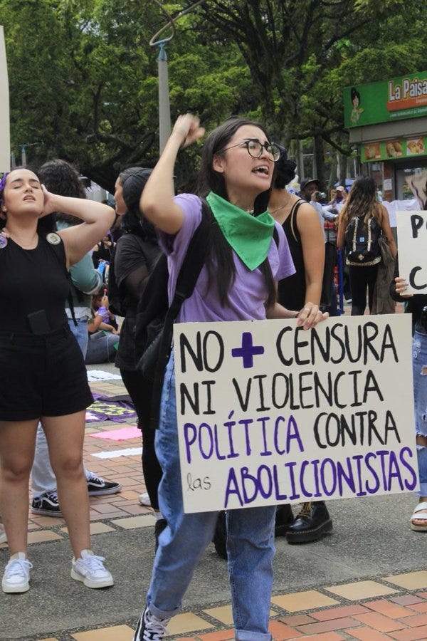 Marcha del 8M en Ecuador, manifestante lleva cartel que dice "No+ ensura ni violencia política contra las abolicionistas"