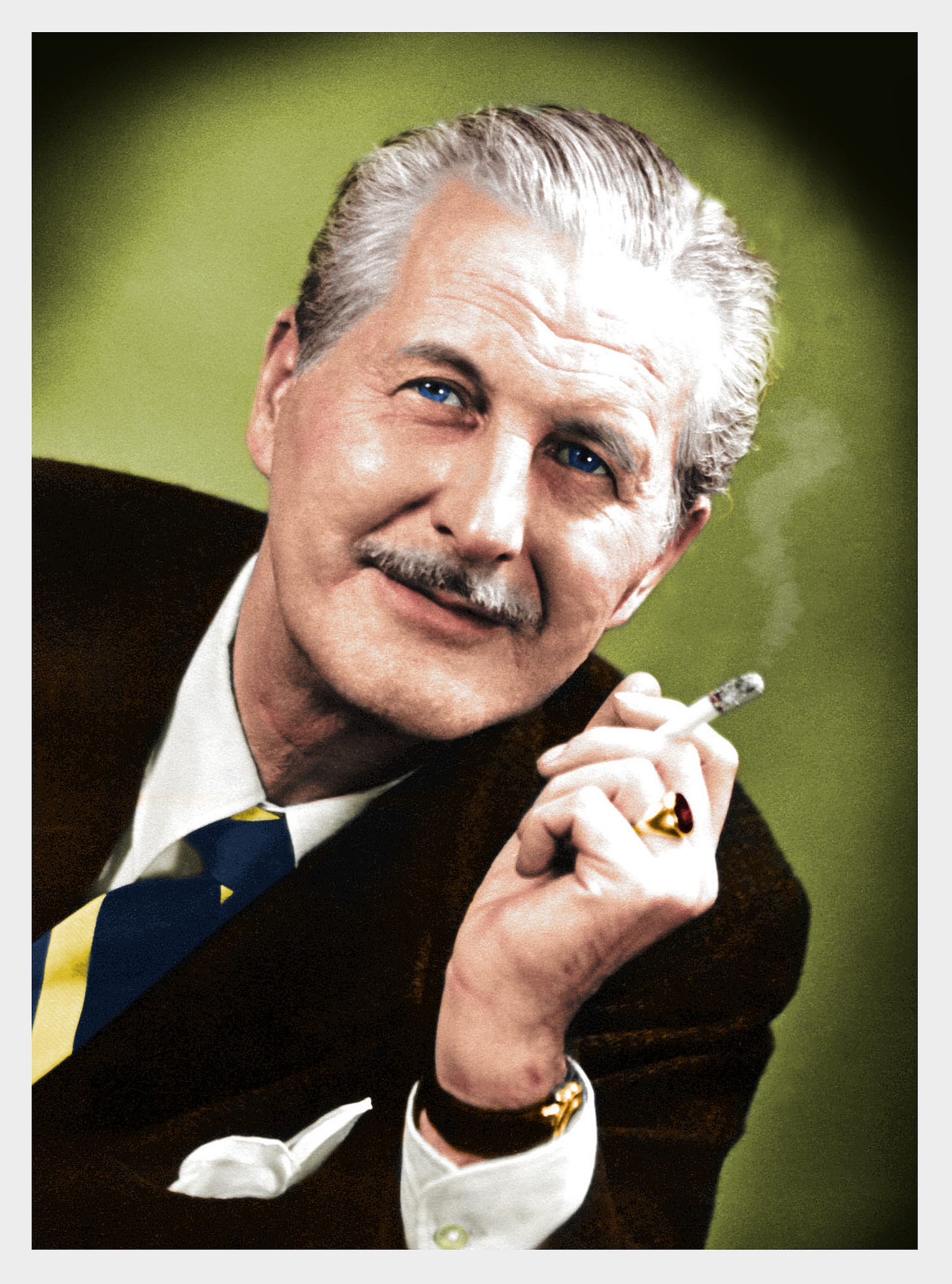 A man with blue eyes, grey hair and a moustache smoking a cigarette.