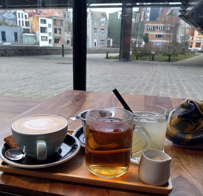 Picture of coffee and tea on a wooden table overlooking a view of Flemish houses