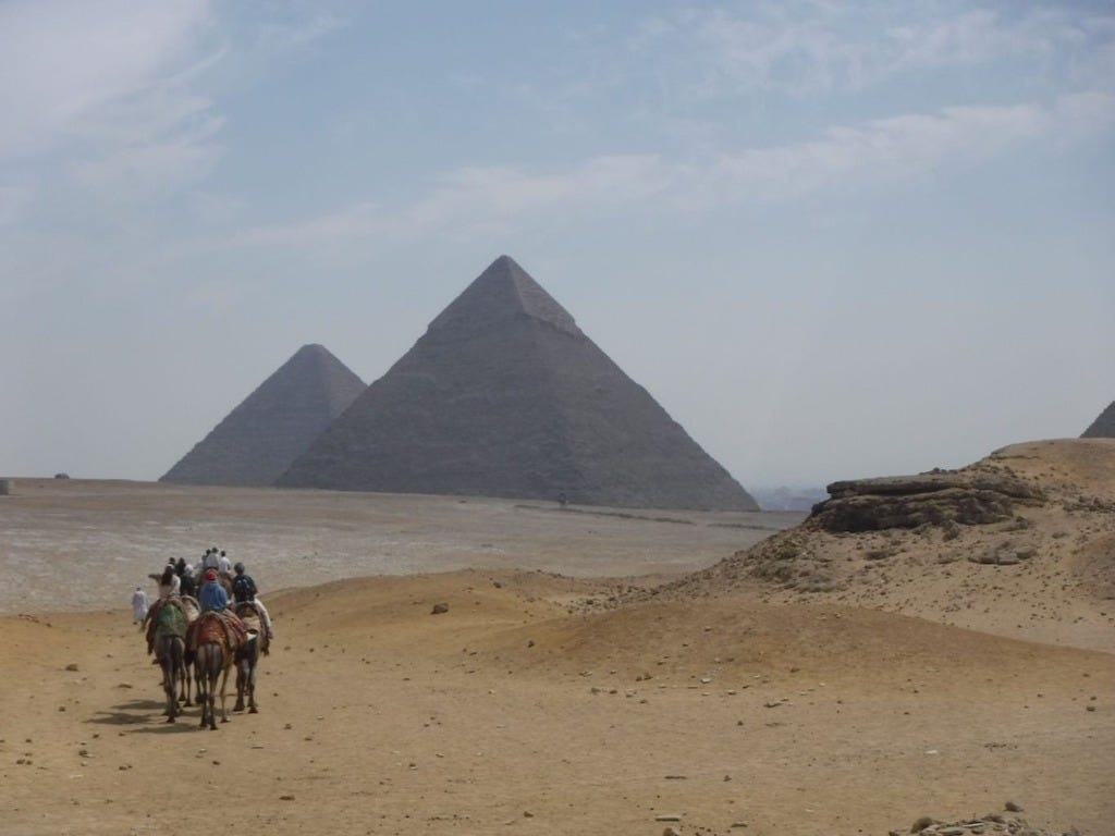 A group of tourists on camels walking towards the pyramids in Egypt. 