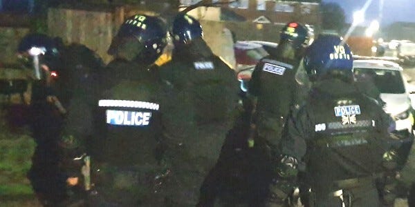Several officers wearing protective uniform and helmets at night