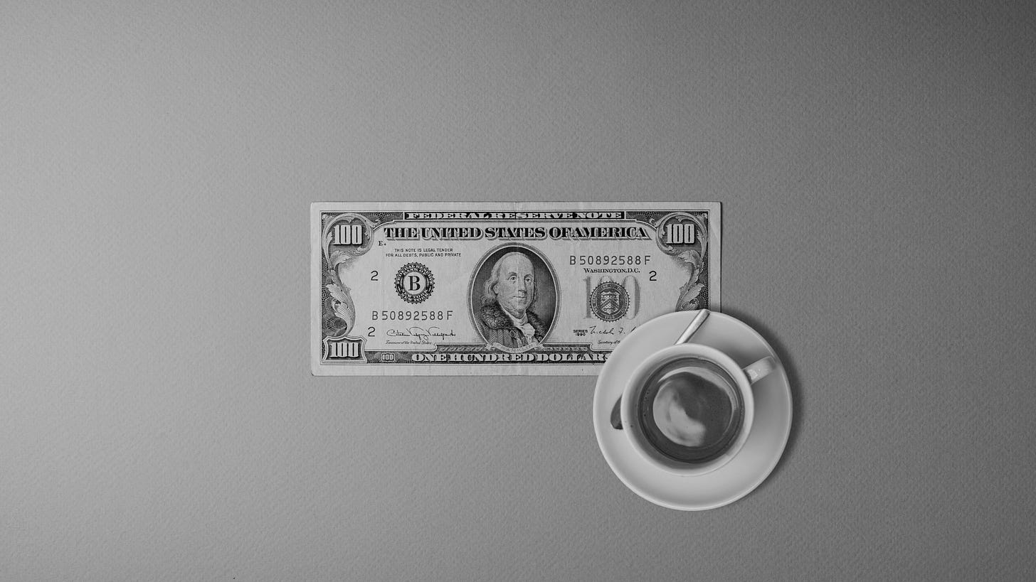 A $100 bill overlaid with a cup of espresso, seen from above