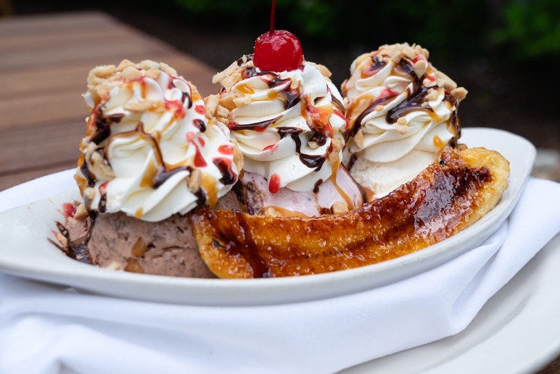 A banana split with multiple sauces, almonds, and a cherry on top