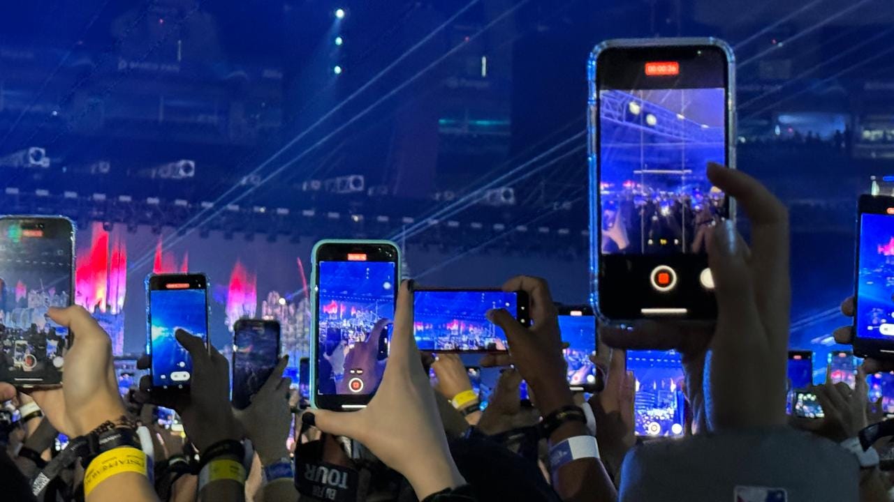 Imagem: Varias pessoas segurando celular para filmar o palco.