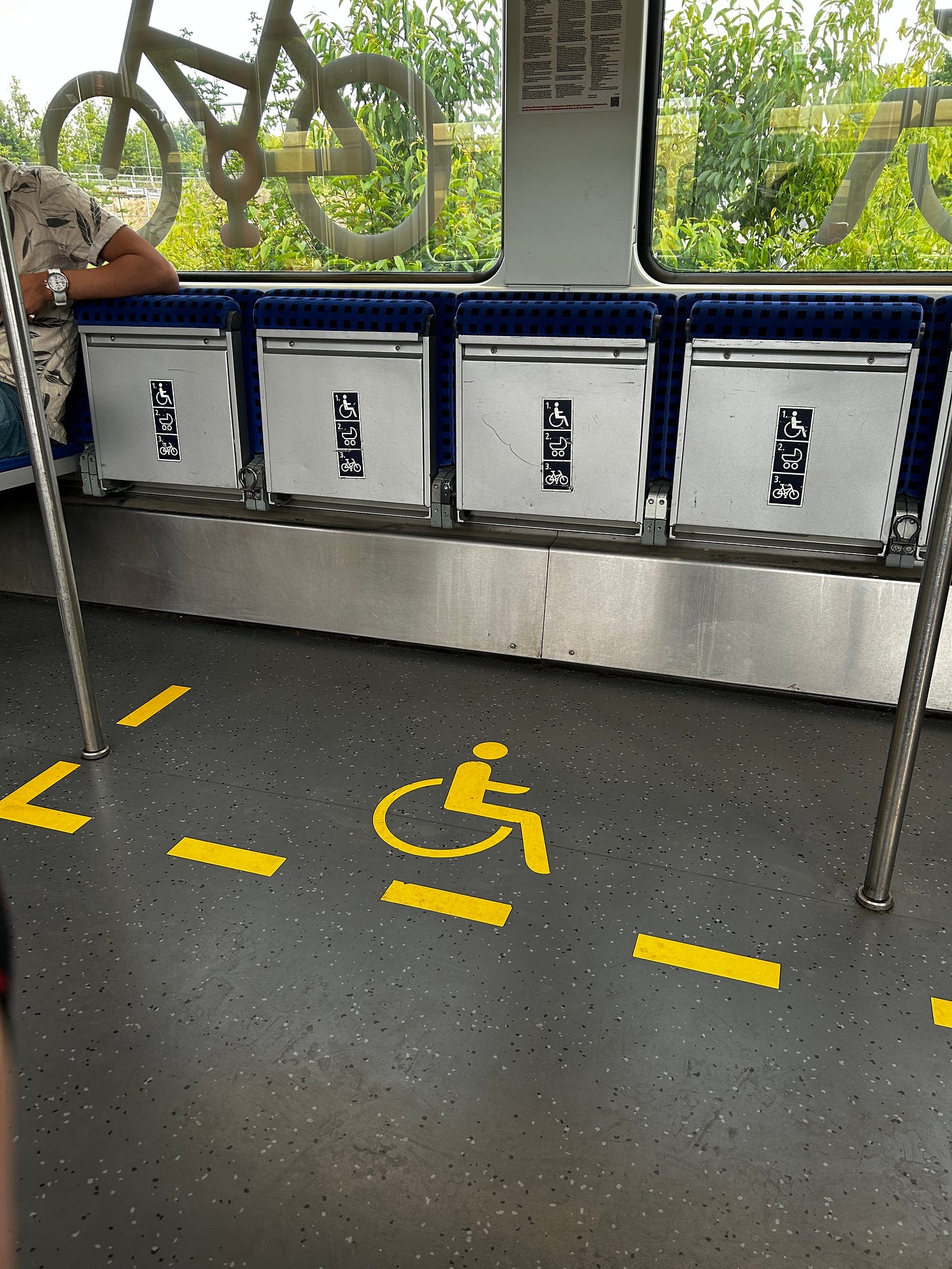 Wheelchair space marked in yellow on the floor, poles in the middle
