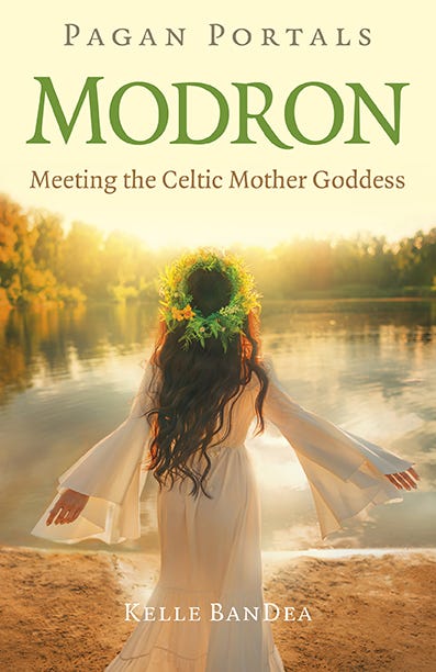 Book cover for Pagan Portals Modron: Meeting the Celtic Mother Goddess by Kelle BanDea. The cover includes an image of a woman from the back, facing away from the camera. She is outdoors at the edge of a lake, wearing a long white robe. She has long, dark hair.