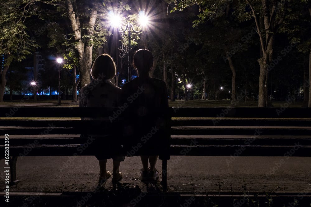 Two women sitting with their backs to the camera on a bench in a night park  in the light of street lamps Stock Photo | Adobe Stock