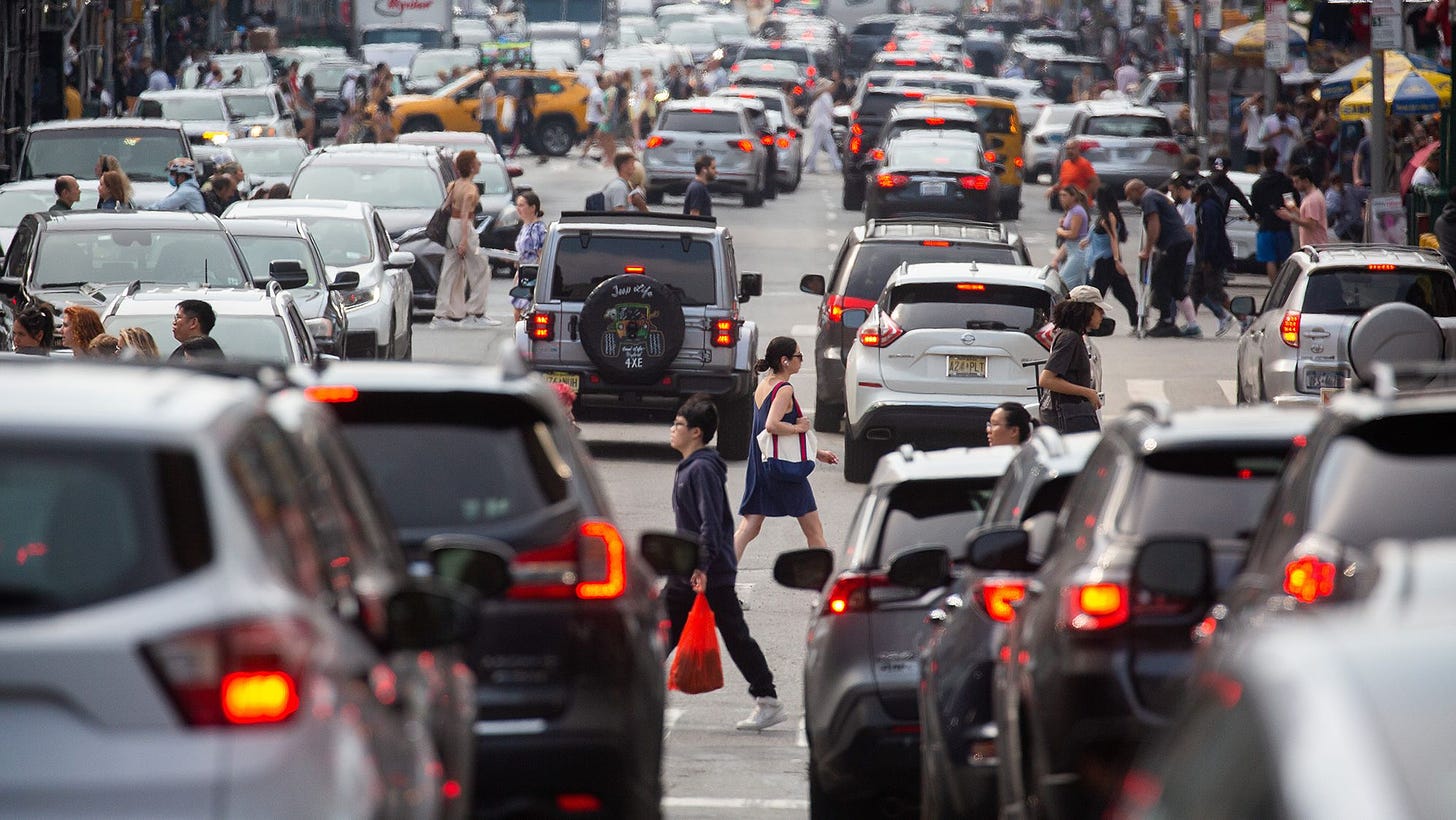 Pedestrians cross a street past traffic in the Chinatown neighborhood of New York, US, on Saturday, June 17, 2023. New York City's congestion pricing plan for the central business district is expected to get final approval this month.