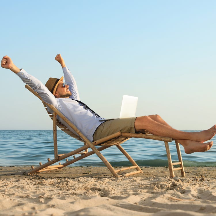 Man on beach with laptop celebrating writing success - concept of loving writing